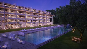 A modern hotel with multiple floors, a swimming pool, and outdoor seating areas.