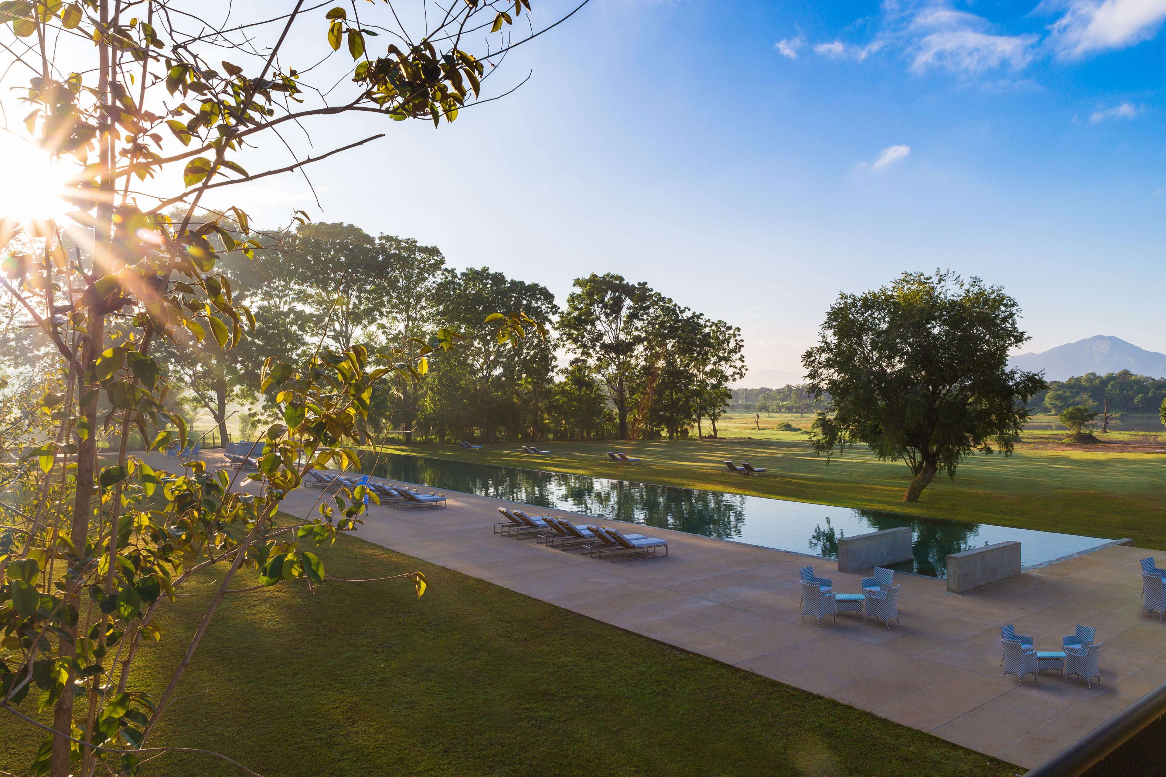 A serene outdoor pool area with lounge chairs and a clear view of a mountain in the background.