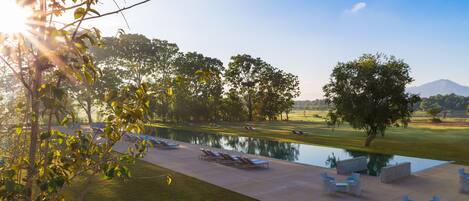 A serene outdoor pool area with lounge chairs and a clear view of a mountain in the background.