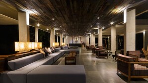 A spacious lounge area with a long sofa, wooden tables, and chairs.