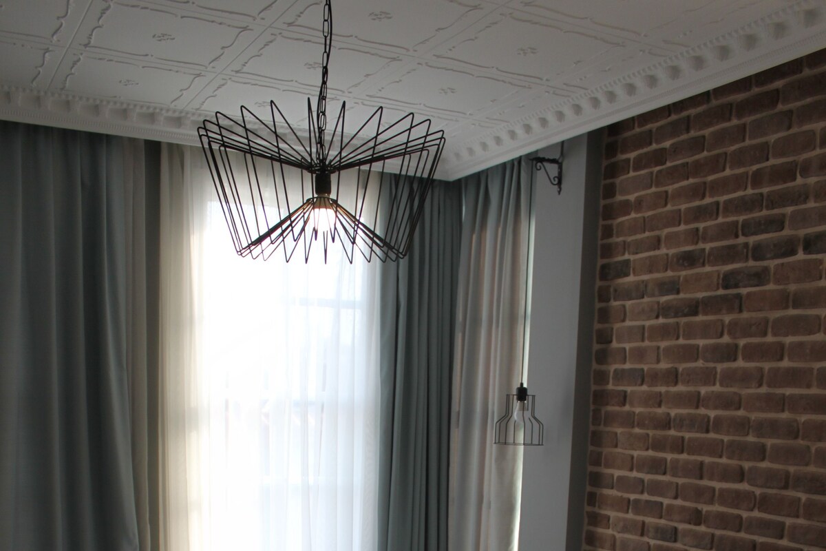 Una habitación de hotel con una cama grande, una pared de ladrillo y una araña.