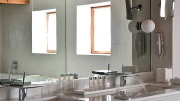 A modern bathroom with a large mirror, two sinks, and a shower.
