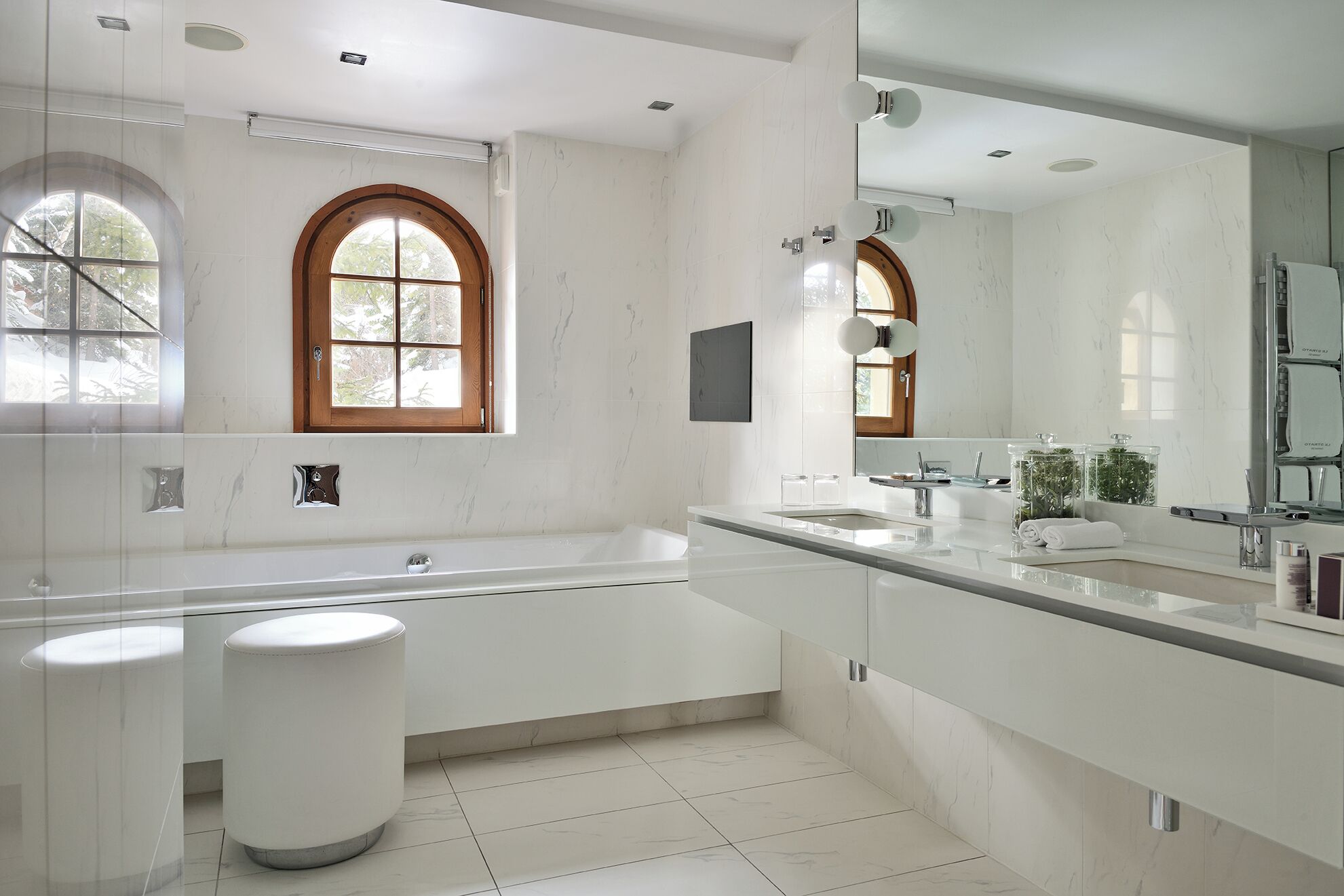 A modern bathroom with a large bathtub, two sinks, and a vanity with a mirror.