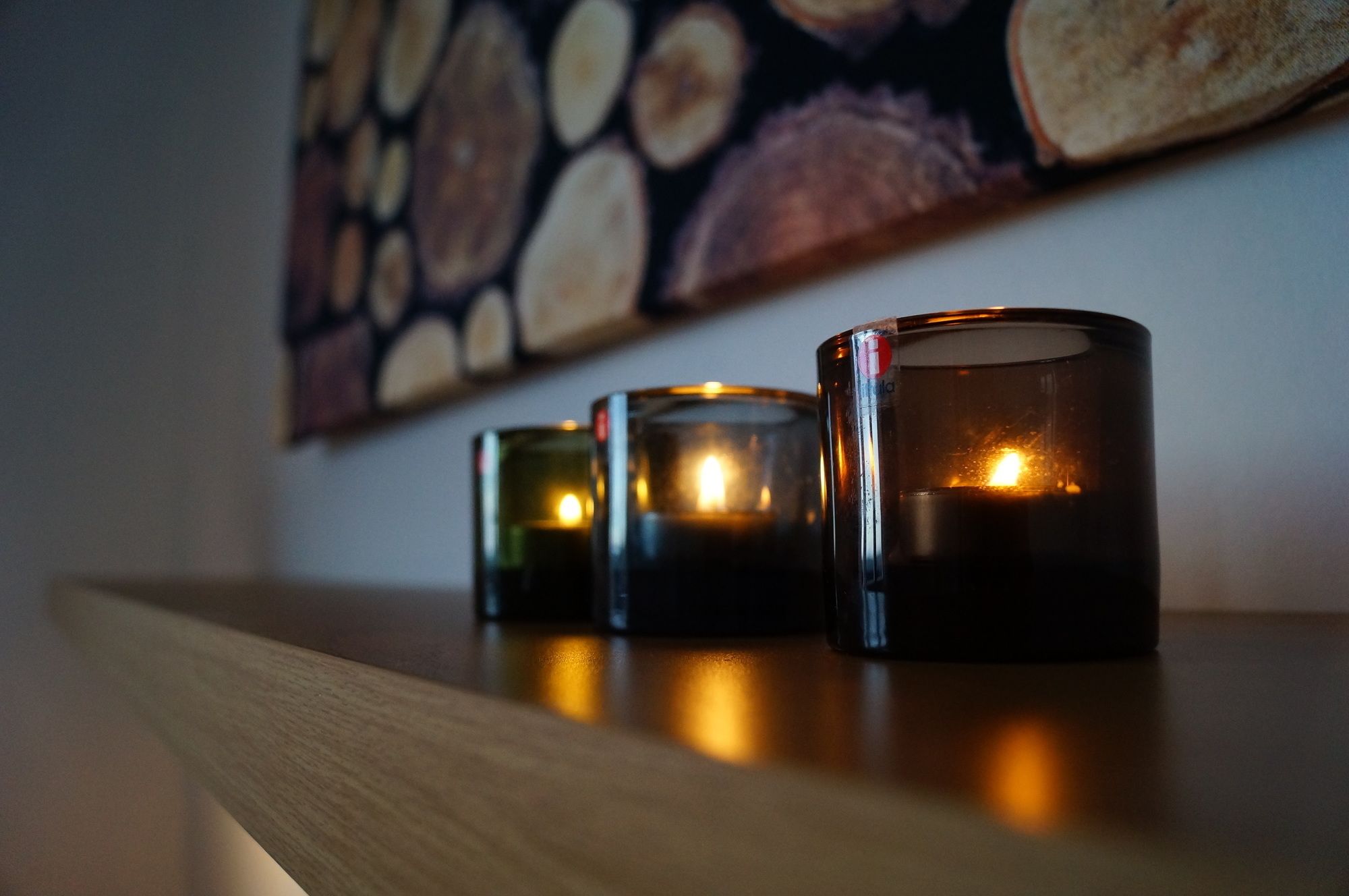 Cuatro velas sobre una estantería de madera.
