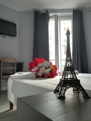 A hotel room with a bed, a small Eiffel Tower model, and a bouquet of flowers. - Hôtel Du Globe 18 (Paris)
