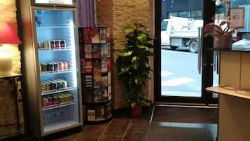 A reception area with a vending machine, a potted plant, and a display of magazines.
