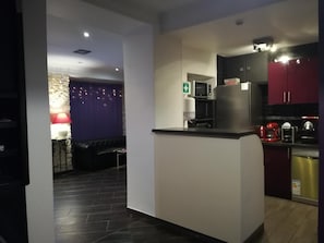 A modern kitchen with dark cabinets, a refrigerator, and a microwave. - Hôtel Du Globe 18 (Paris)