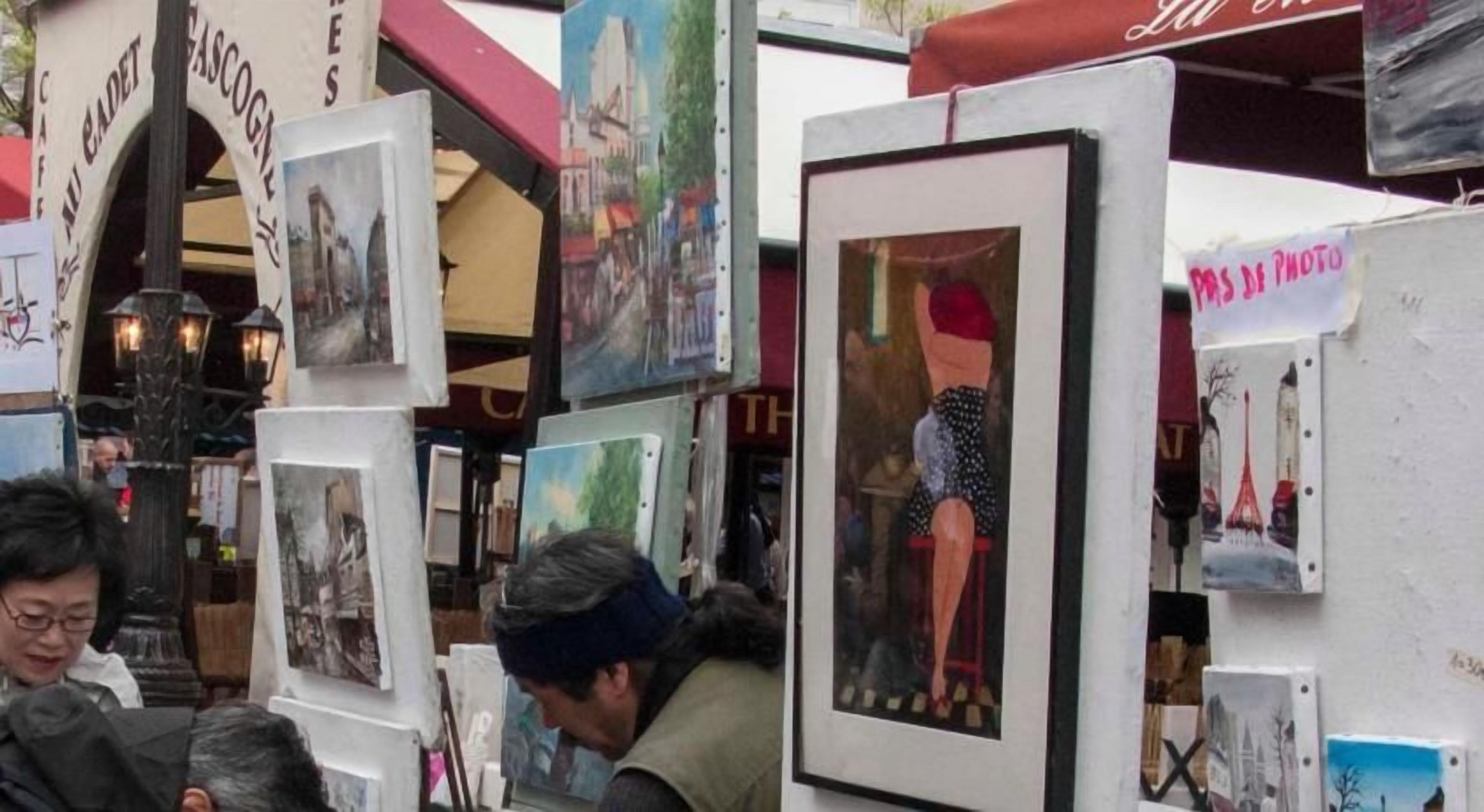 A market stall with various framed artworks on display.