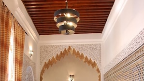 A bedroom with a large bed, wooden headboard, patterned walls, and a wooden ceiling. - Riad Dar Soufa (Rabat)