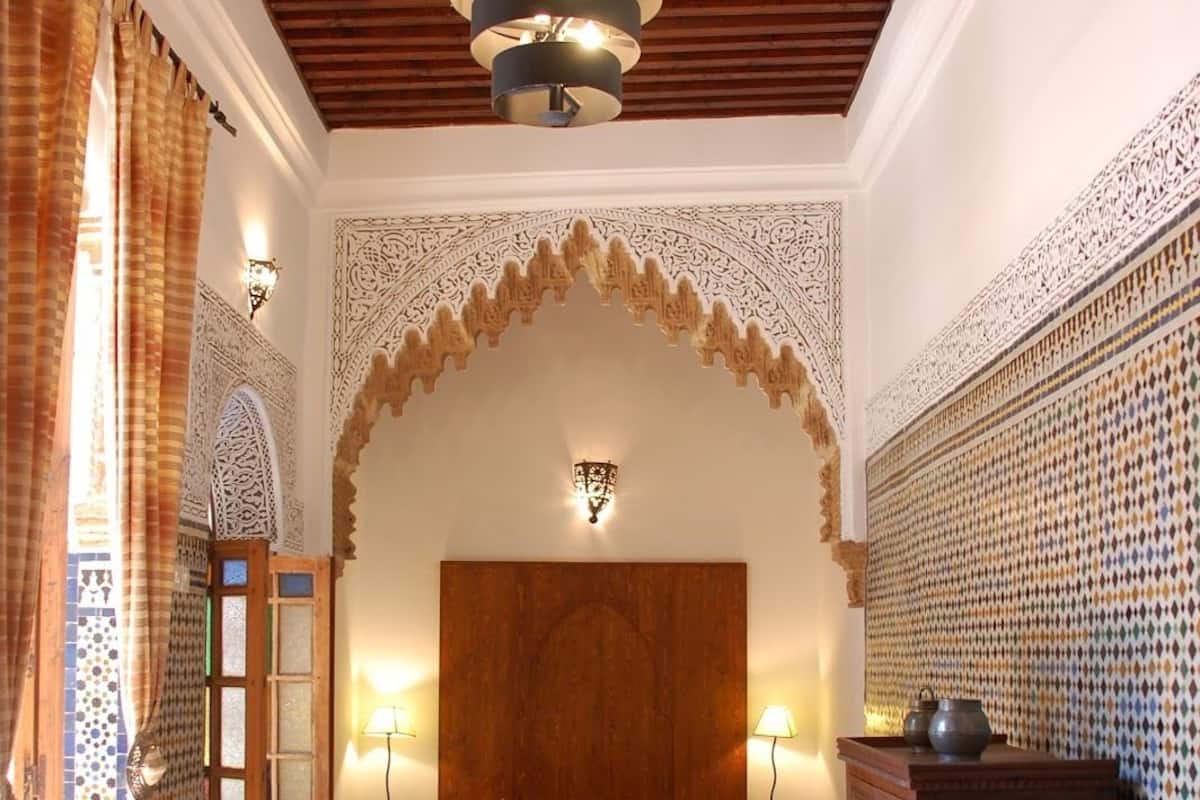 Un dormitorio con una cama grande, cabecera de madera, paredes con estampado y techo de madera.