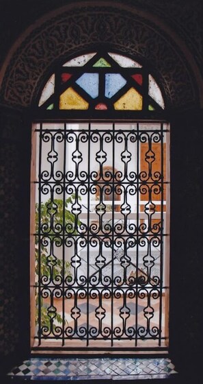 A window with a decorative metal grille and a stained glass design.
