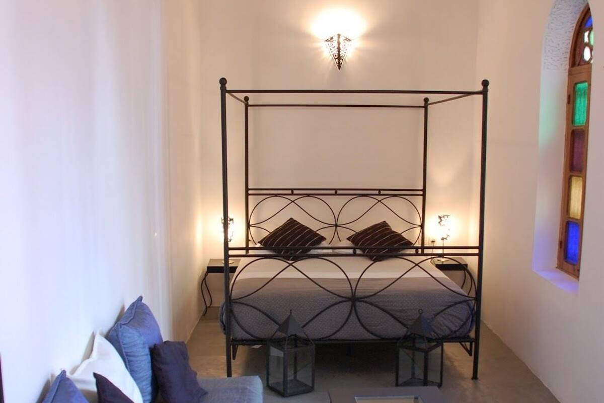 Un dormitorio con cama con dosel, un sofá y una mesa de centro.