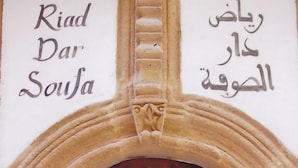 A wooden door with metal studs, set within an arched doorway with decorative stone carvings. - Riad Dar Soufa (Rabat)
