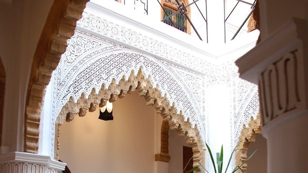 An indoor courtyard with a checkered floor, a table with chairs, a sofa with cushions, and a lamp. - Riad Dar Soufa (Rabat)