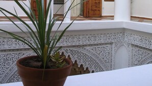 A courtyard with ornate wooden doors and intricate white patterns on the walls. - Riad Dar Soufa (Rabat)