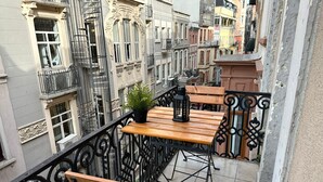 A balcony with wooden furniture, a potted plant, and a lantern. - Taksim Park  (Istanbul)