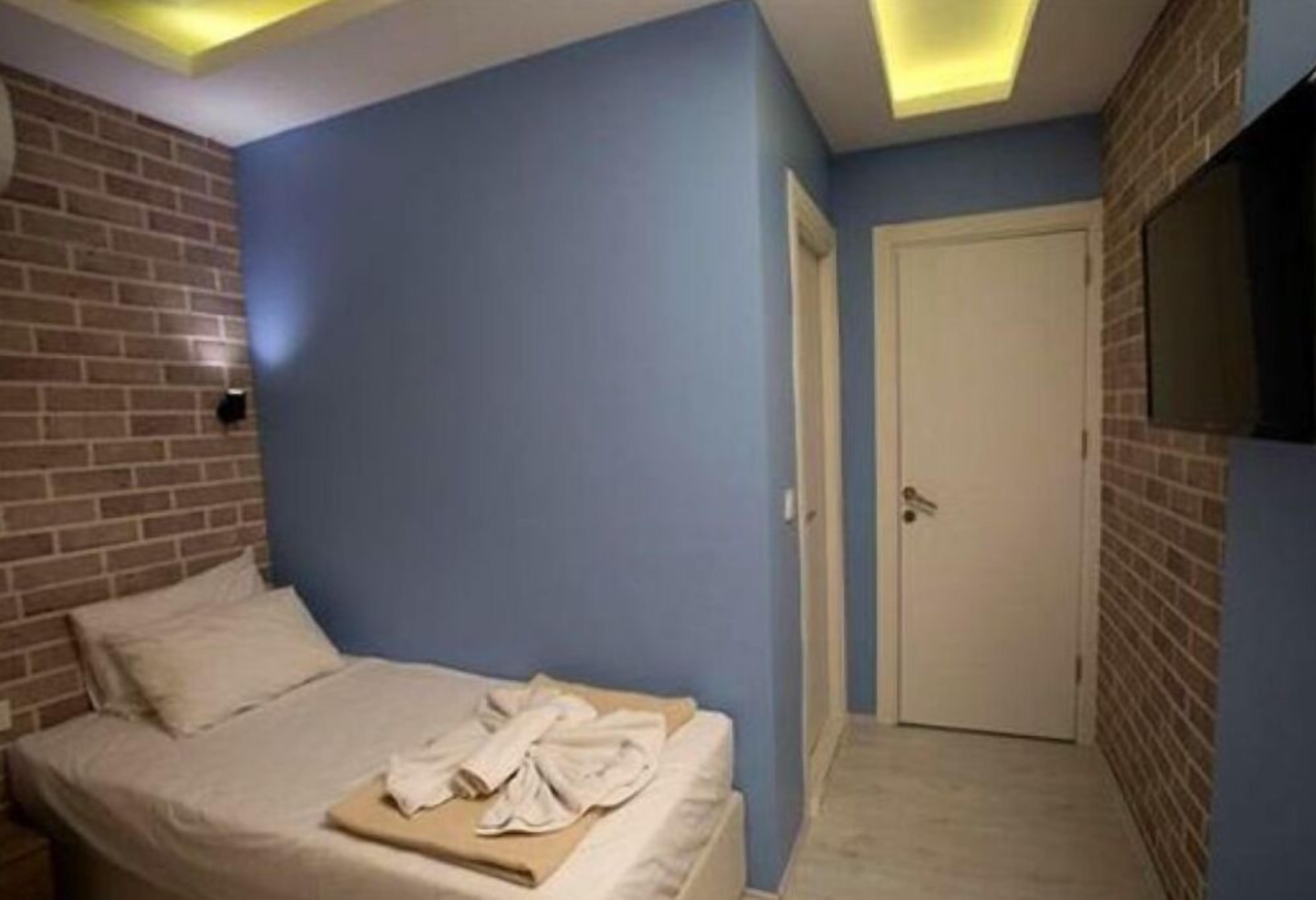 Een slaapkamer met een wand van baksteen, een bed met een witte dekbedovertrek en een wandmontage flatscreen-tv.