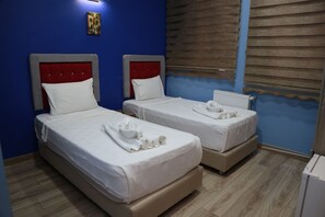 Une chambre d’hôtel avec deux lits, chacun doté d’une tête de lit rouge, de draps blancs et de serviettes.