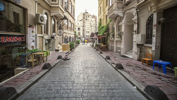 A cobblestone street lined with buildings, some with outdoor seating and plants. - Taksim Park  (Istanbul)