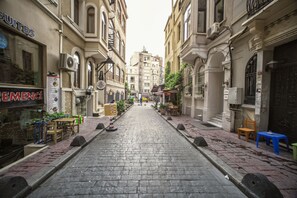 Une rue pavée bordée d’immeubles, dont certains sont dotés de terrasses et de plantes.
