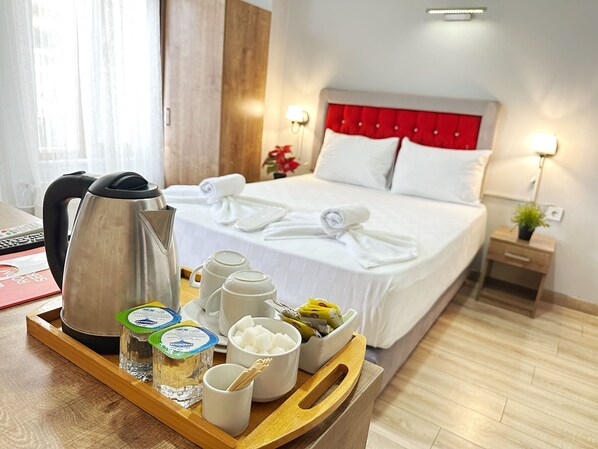 Une chambre d’hôtel avec un lit, des lampes de chevet, un plateau avec des aliments et une bouilloire.