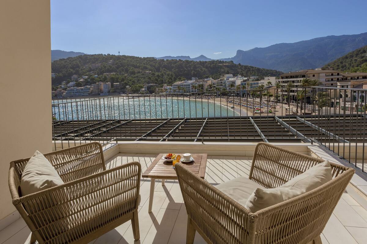 A balcony with wicker furniture and a table with a drink and fruit.
