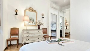 A bedroom with a large bed, a dresser, two chairs, a mirror, and a vase with flowers. - My Guest In Florence (Florence)