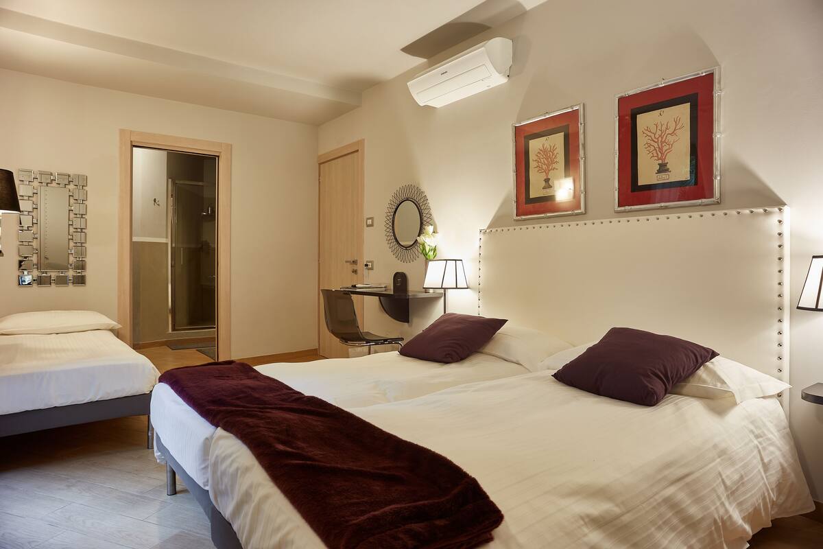 Et hotelværelse med to senge, et skrivebord og et spejl.