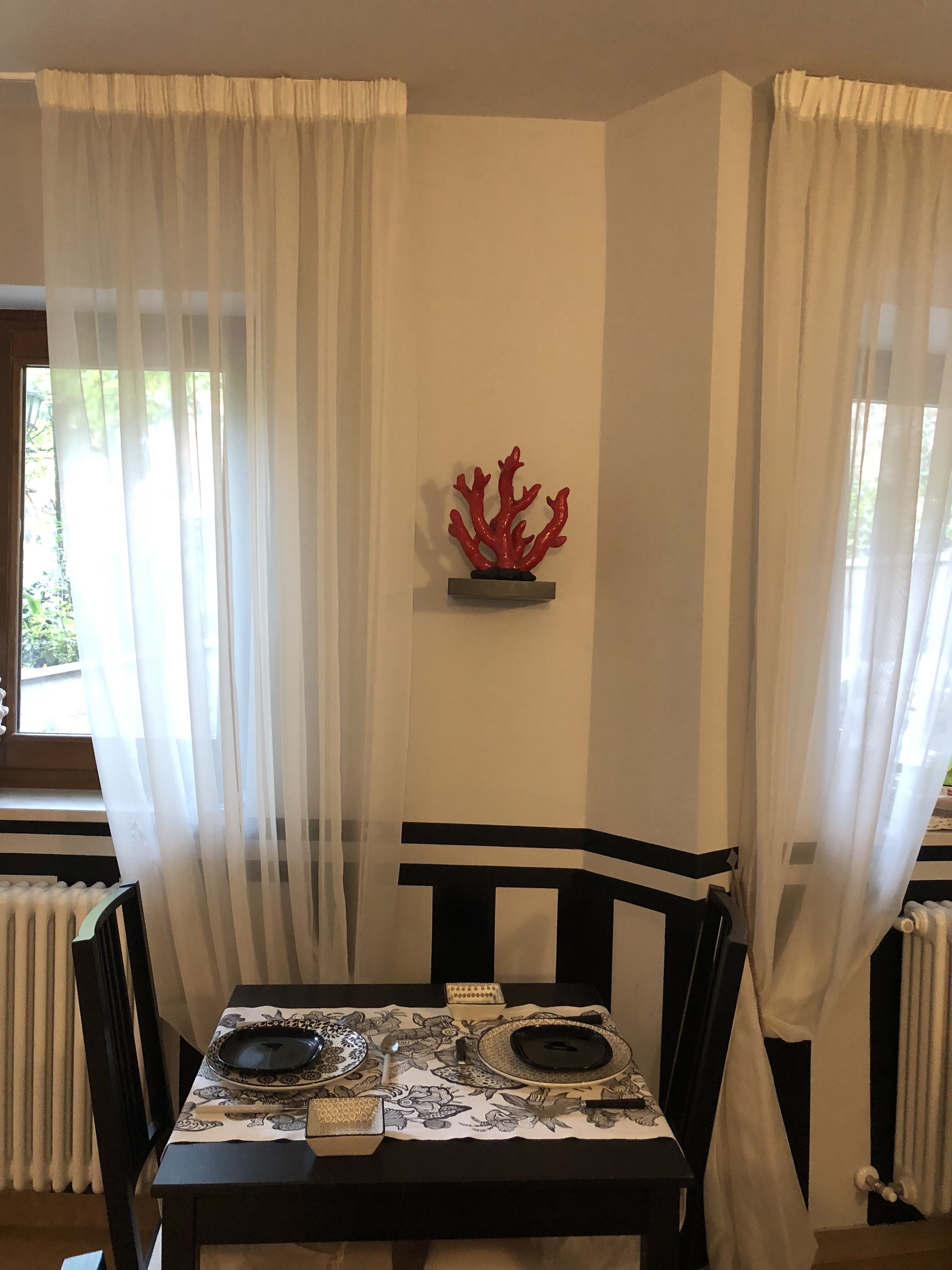 A dining area with a table set for two, featuring a patterned tablecloth and a decorative coral piece on the wall.