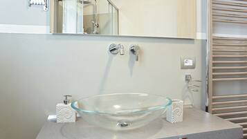 A modern bathroom with a glass bowl sink, a mirror, and a towel rack.