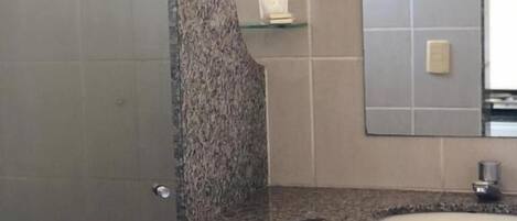 Une salle de bain avec un comptoir en granit, un lavabo, un miroir et un porte-serviettes.