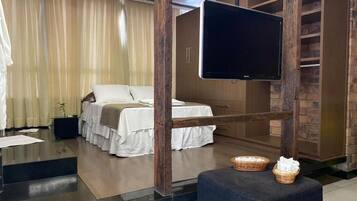 A hotel room with a bed, a television, a wardrobe, and a small table with baskets.