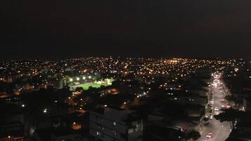A nighttime cityscape with a densely populated area, illuminated streets, and a prominent road running through the center.