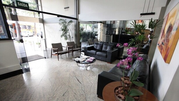 Un hall d’entrée moderne avec un canapé en cuir noir, une table basse et un pot d’orchidée.