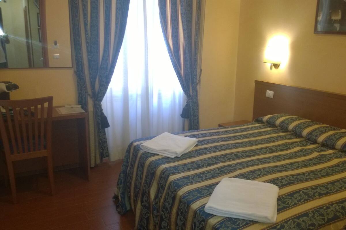 A hotel room with a bed, a desk, and a chair.