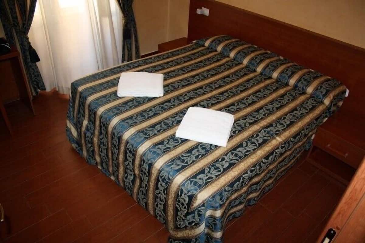 A hotel room with a bed featuring a patterned bedspread and two neatly folded white towels.