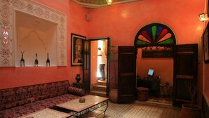 A room with a patterned sofa, a small table, a decorative mirror, and a colorful wall mural.