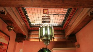 A room with a high ceiling, a skylight, and a green patterned chandelier.