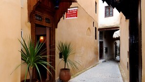 A narrow alleyway with a building entrance featuring a wooden door and a signboard.