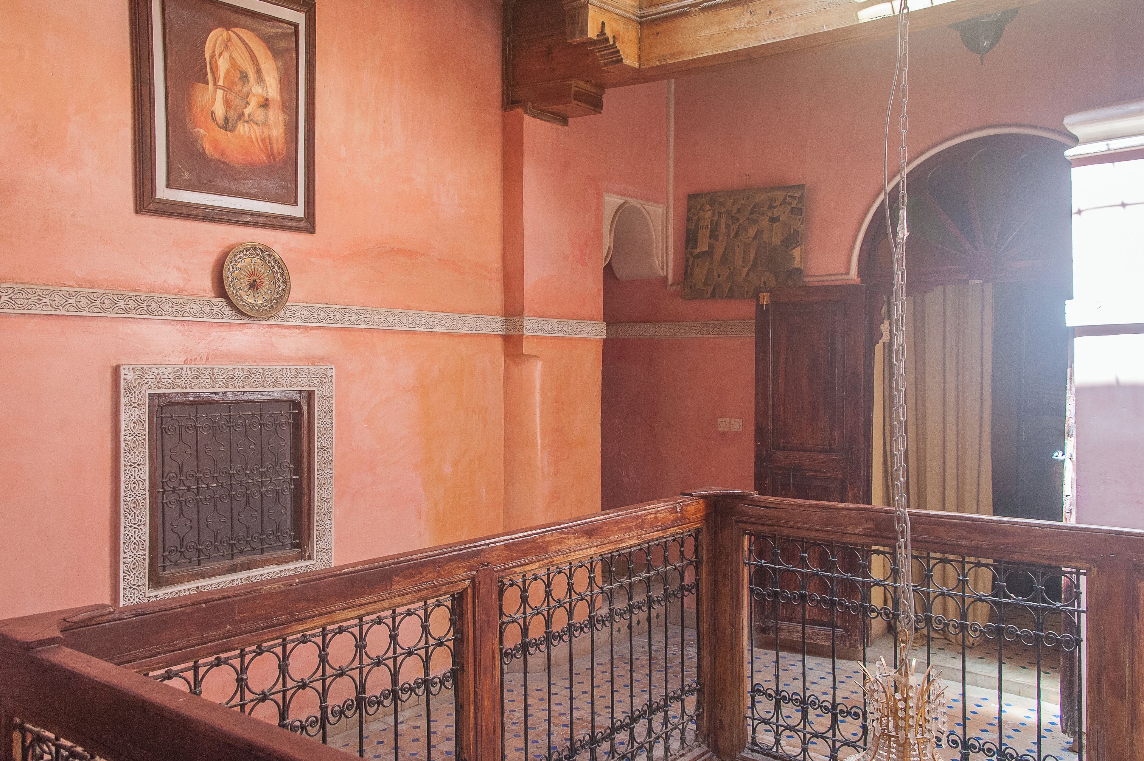A staircase with ornate metal railings, a decorative wall with a framed artwork, and a patterned floor.