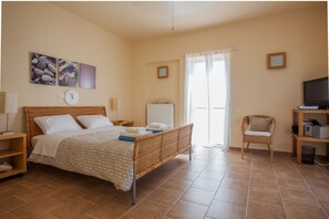 Une chambre à coucher avec un lit, une chaise, une télévision et une étagère.