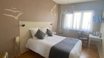 Un dormitorio con una cama, un escritorio y una silla.