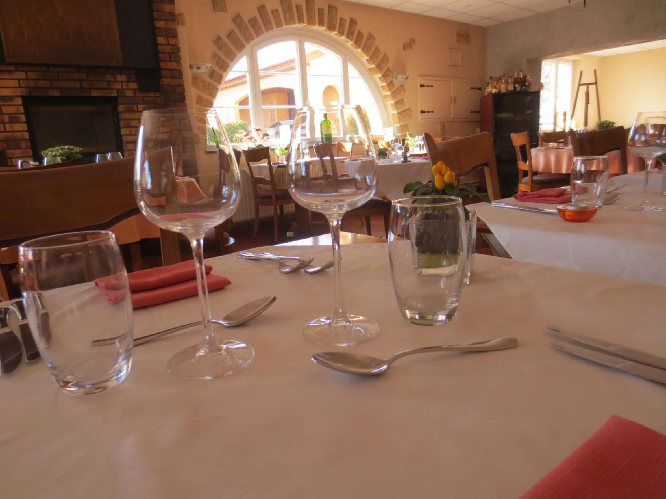 A restaurant table set with wine glasses, cutlery, and a vase with flowers.