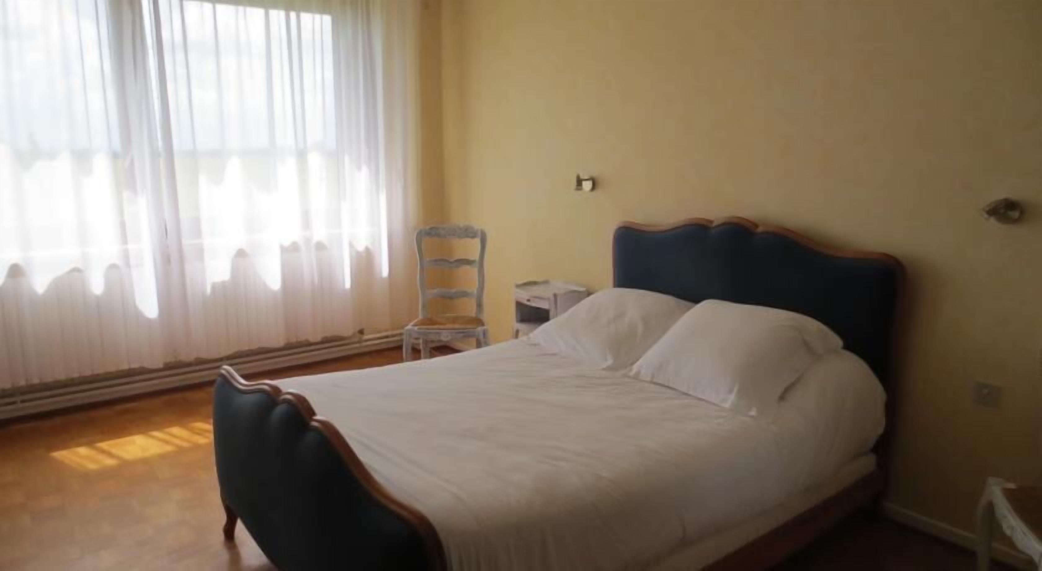 Une chambre à coucher avec un lit, une chaise et une table de chevet.