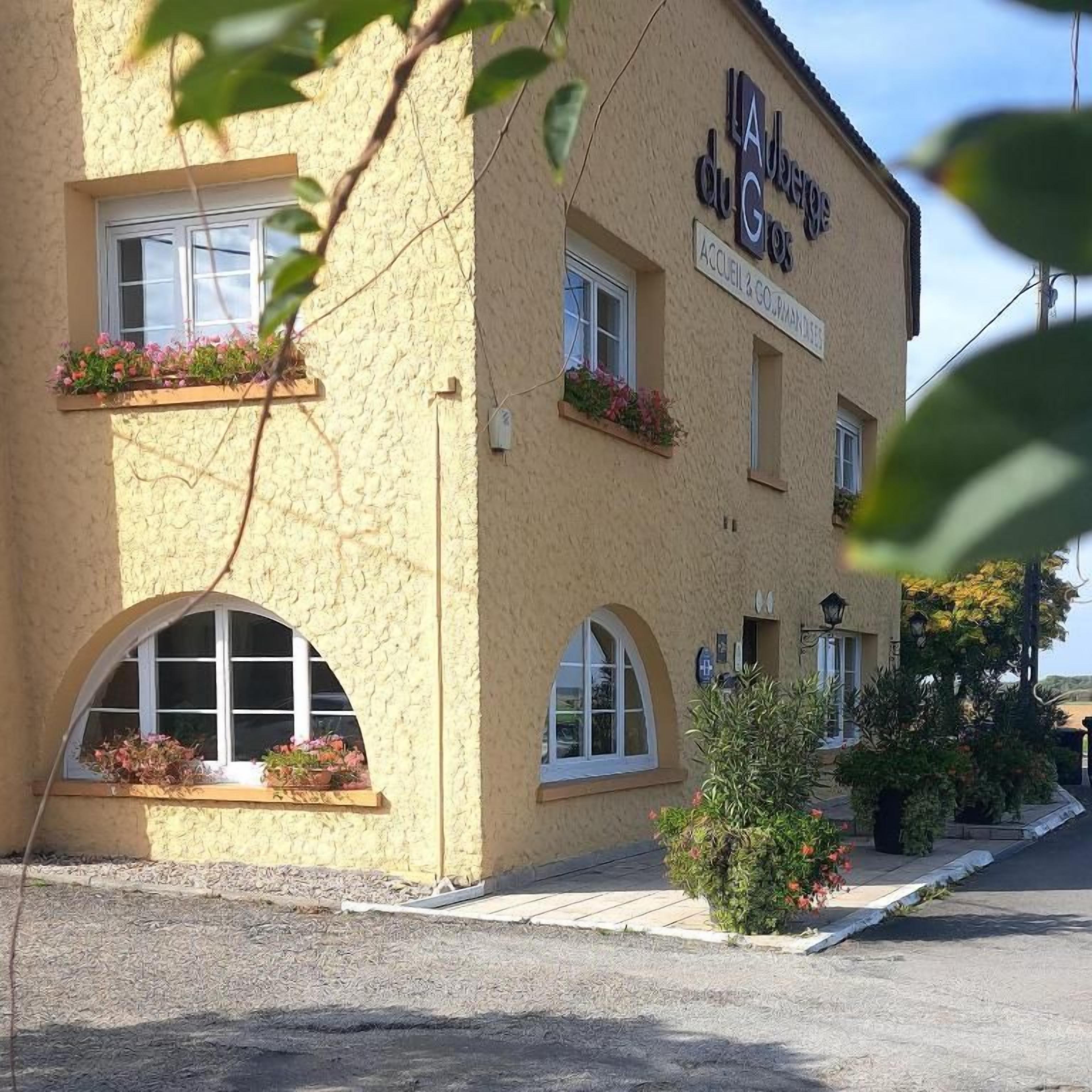 Um edifício com uma placa indicando 'LA Bergerie du Gros' e uma janela com caixas de flores.
