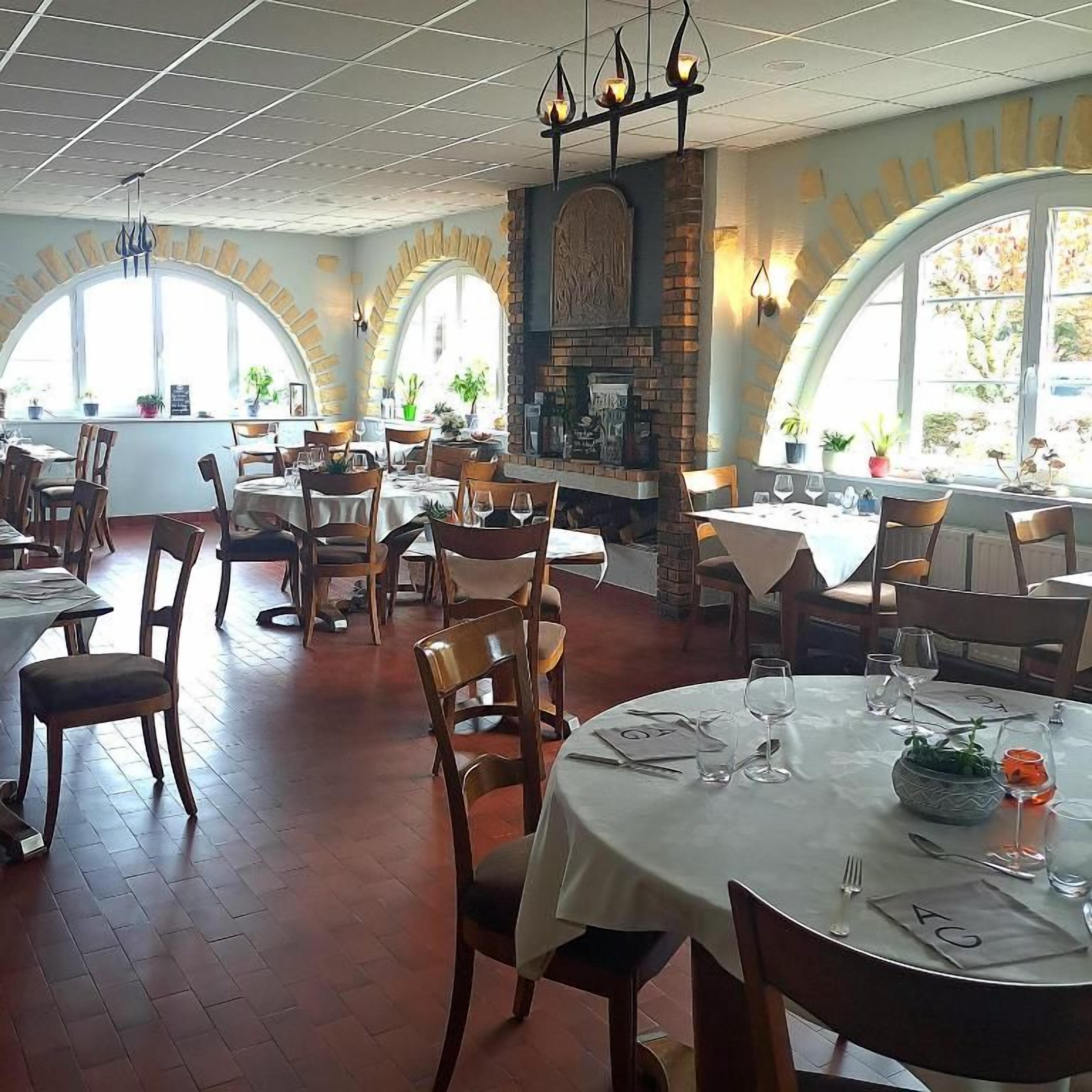 Ein Restaurant mit runden Tischen, Stühlen und einem Kamin aus Ziegelsteinen.