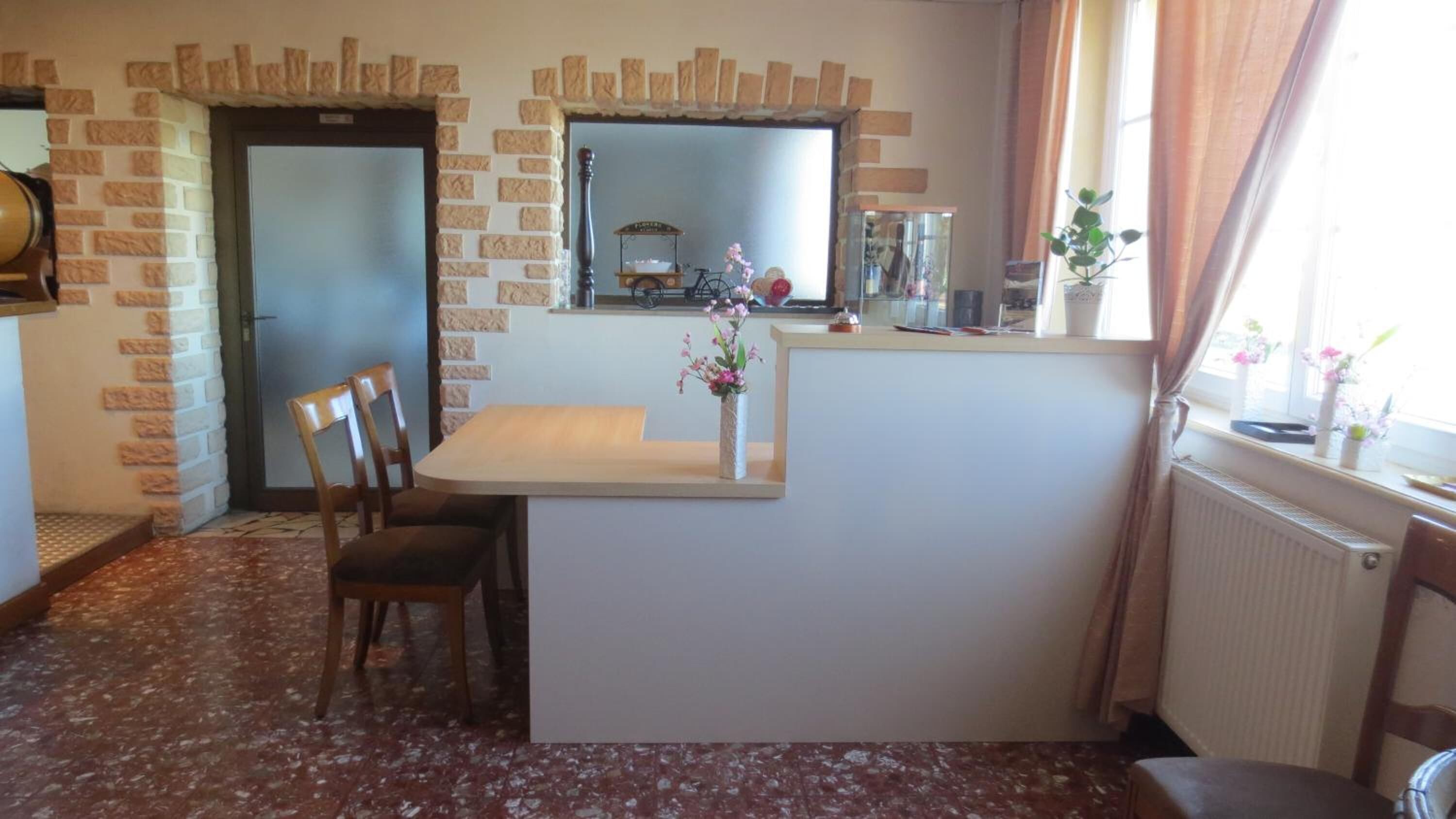 A compact kitchen with a small island, a dining table with chairs, and a window with curtains.