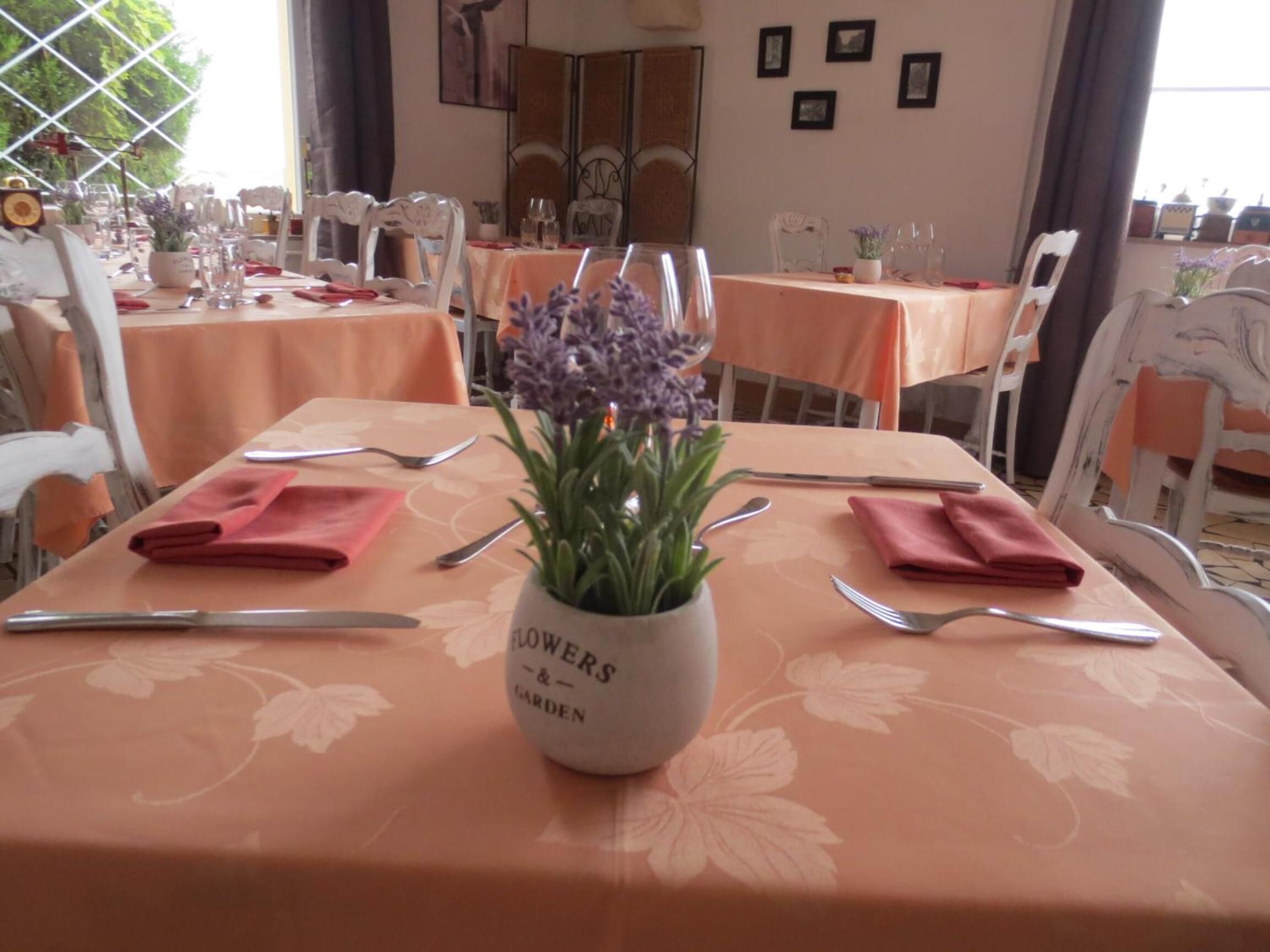 A dining table set with a vase of flowers, red napkins, and cutlery.