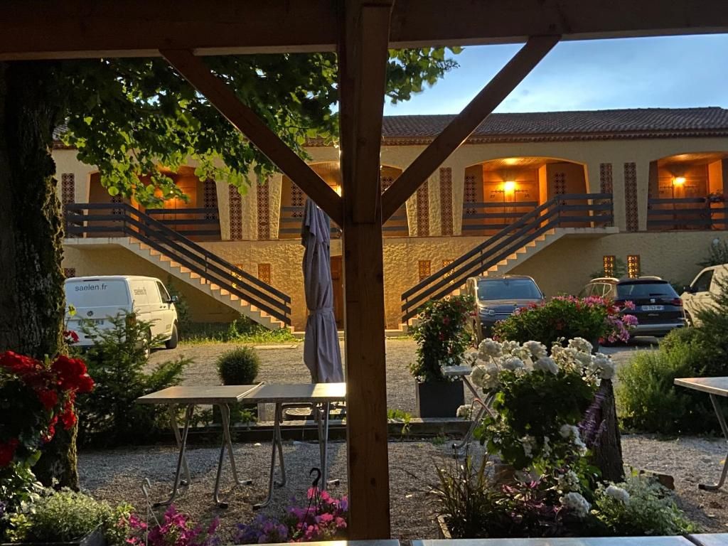 Un'area esterna coperta con una pergola in legno, una scala che conduce a un edificio e un tavolo con sedie.