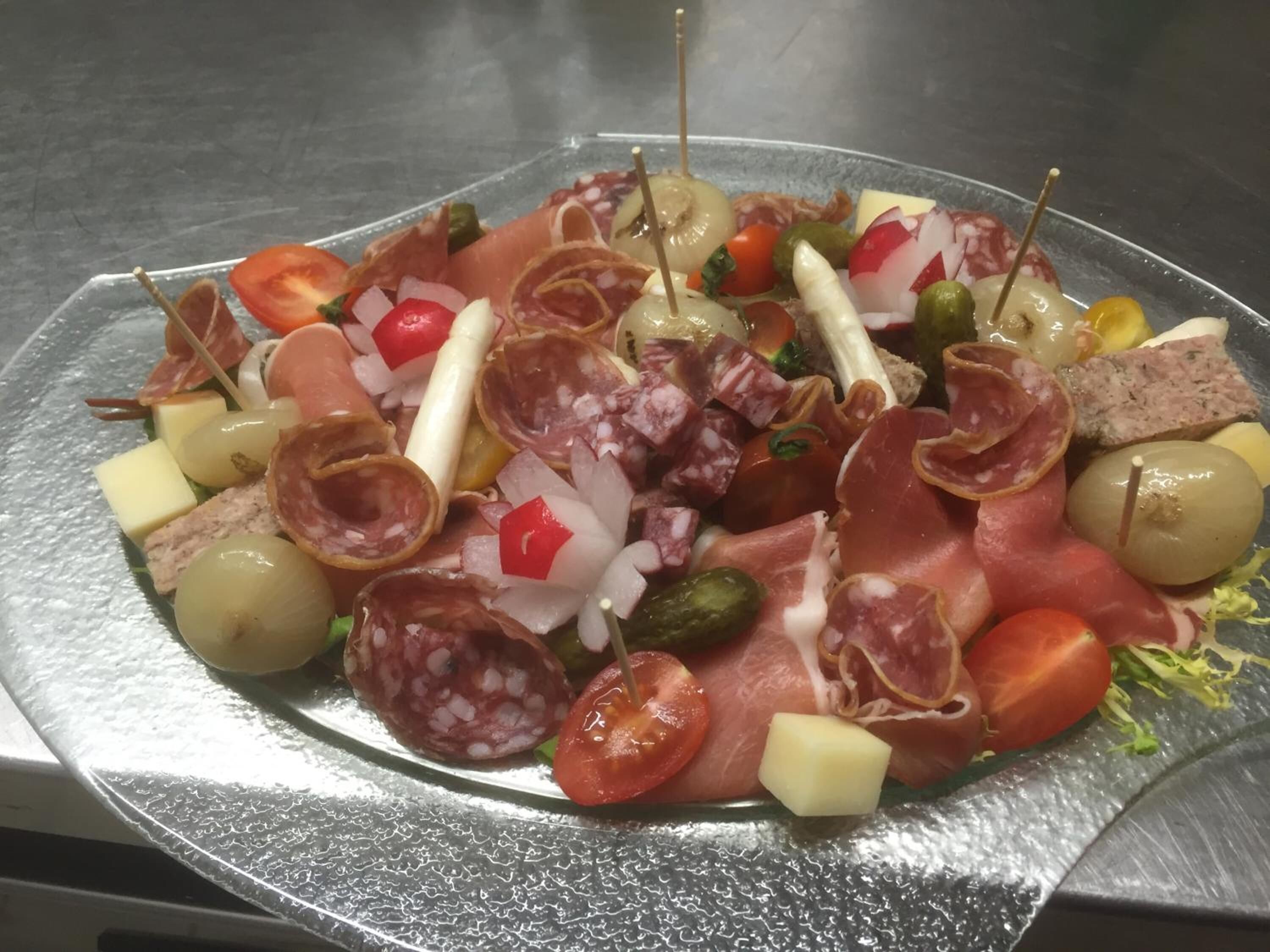 Une assiette de charcuteries et de fromages variés, présentée sur un plateau en métal.